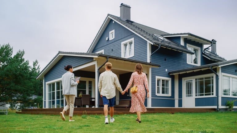 Young Couple Viewing Property for Sale, Talking with Professional Real Estate Agent Outside the House on a Summer Day