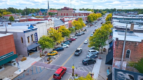 Elevated view of bustling small-town main street with vibrant architecture and early fall foliage