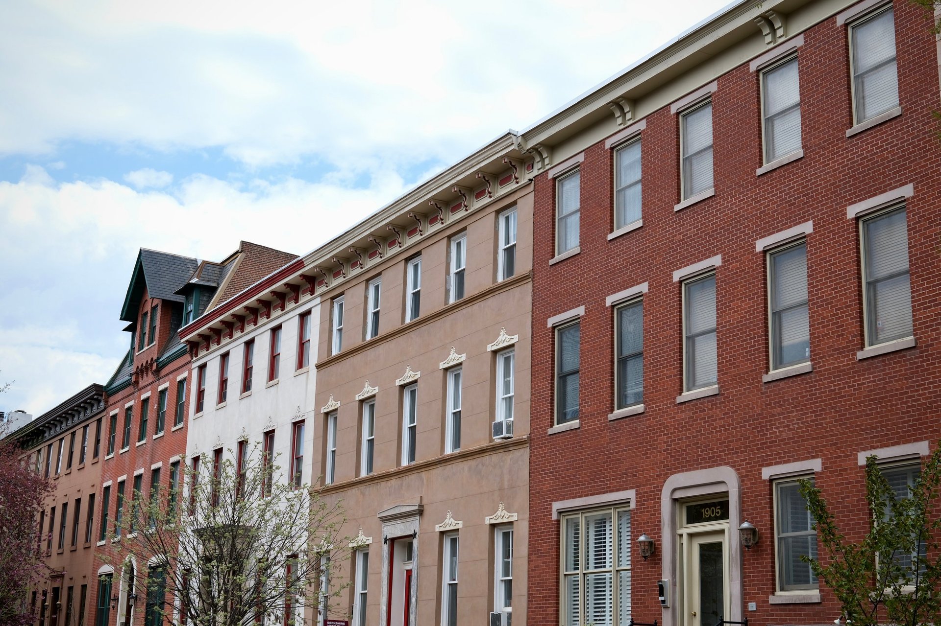 A classic stretch of Philadelphia row houses displays a range of materials and colors, with red brick, white stucco, and ornate beige details.