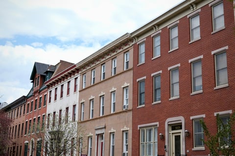 A classic stretch of Philadelphia row houses displays a range of materials and colors, with red brick, white stucco, and ornate beige details.