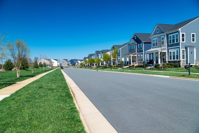 Row of modern detached houses along the road with lawn and sidewalk