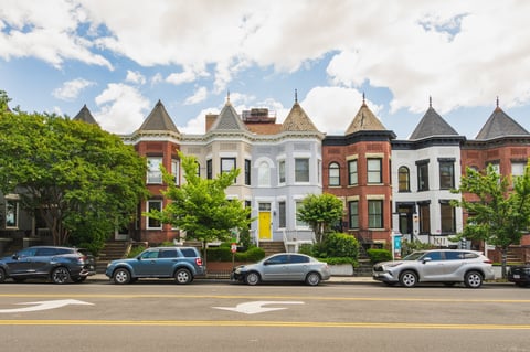 Colorful historic row houses with turrets and bay windows line a sunny street