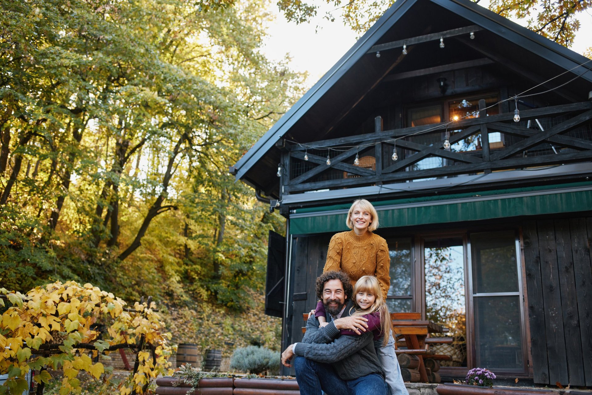 Family is enjoying and posing in front of a cozy cabin during an autumn weekend