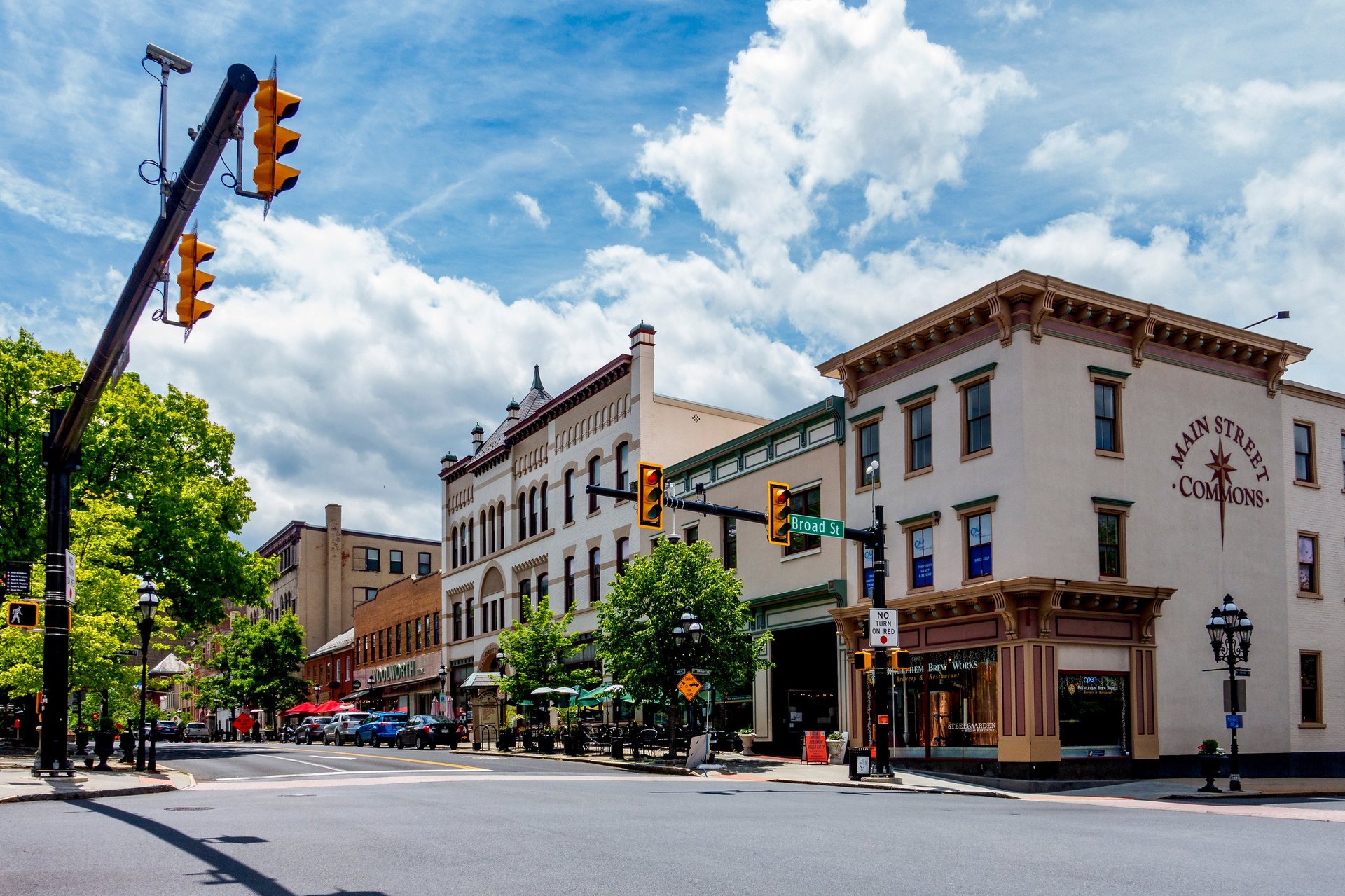 Historic street intersection with historic buildings, traffic light, green trees, and blue sky with white clouds