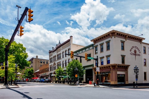 Historic street intersection with historic buildings, traffic light, green trees, and blue sky with white clouds